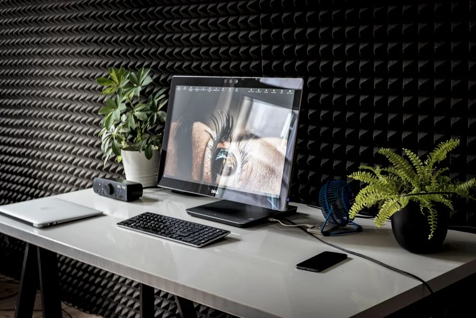 A neat workspace featuring a sketchpad with wireframes, a smartphone, and a keyboard on a wooden desk.